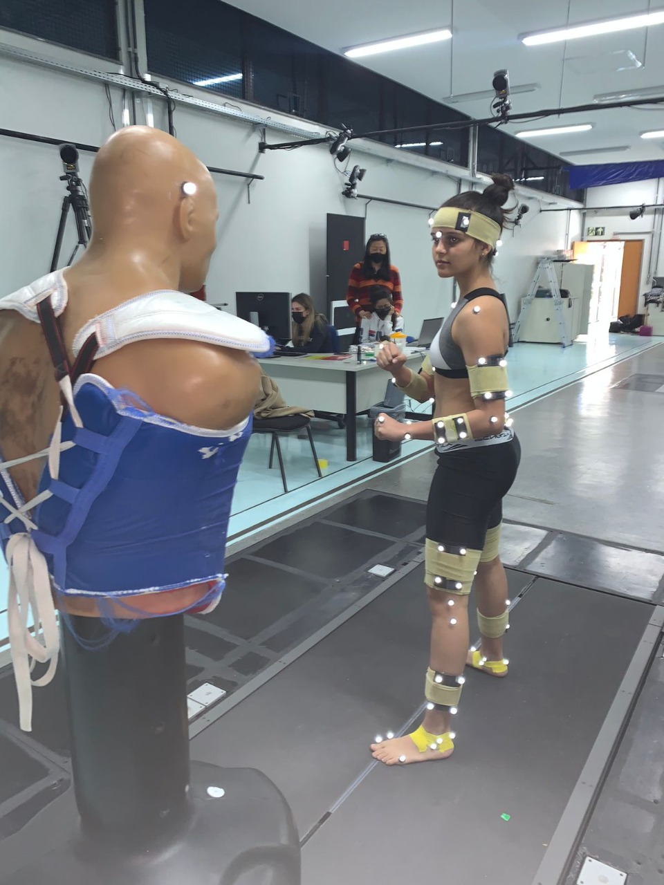 Atleta em sessão de análise cinemática 3D com marcadores reflexivos, em laboratório de biomecânica da UFMG.